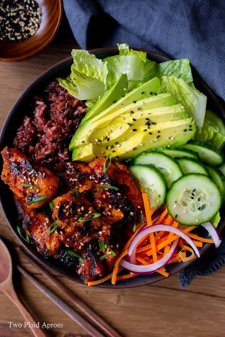 Rice bowl with glazed chicken, avocado, cucumber, lettuce and shredded vegetables